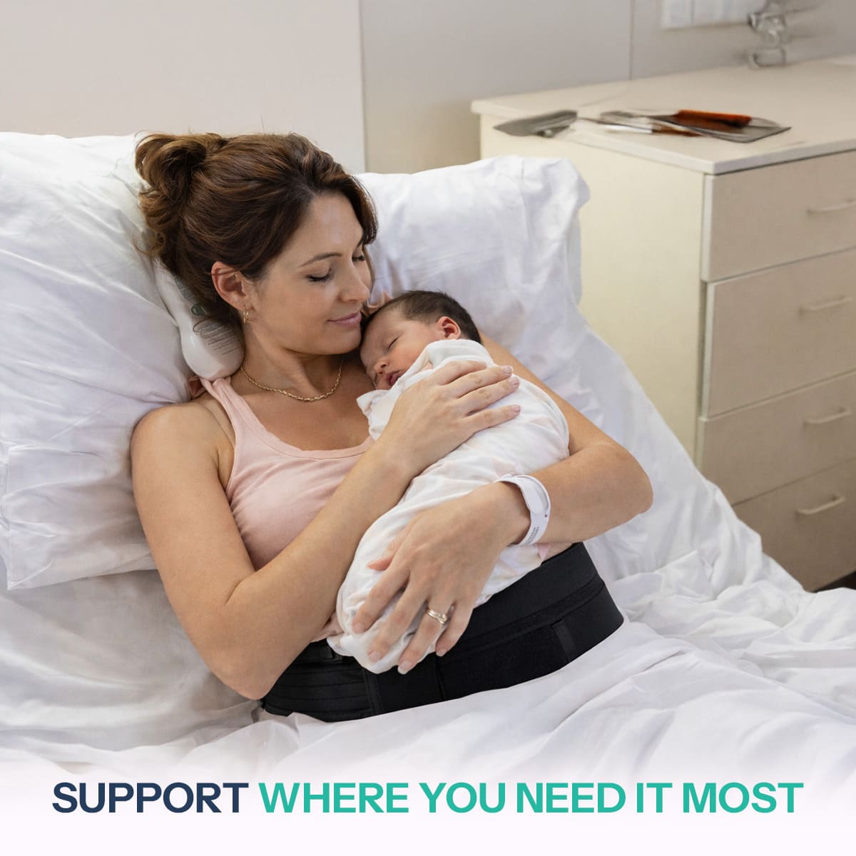 A new mother resting in a hospital bed while holding her newborn baby, wearing the SUPEAK belly band for essential post-operative stability and core recovery support.